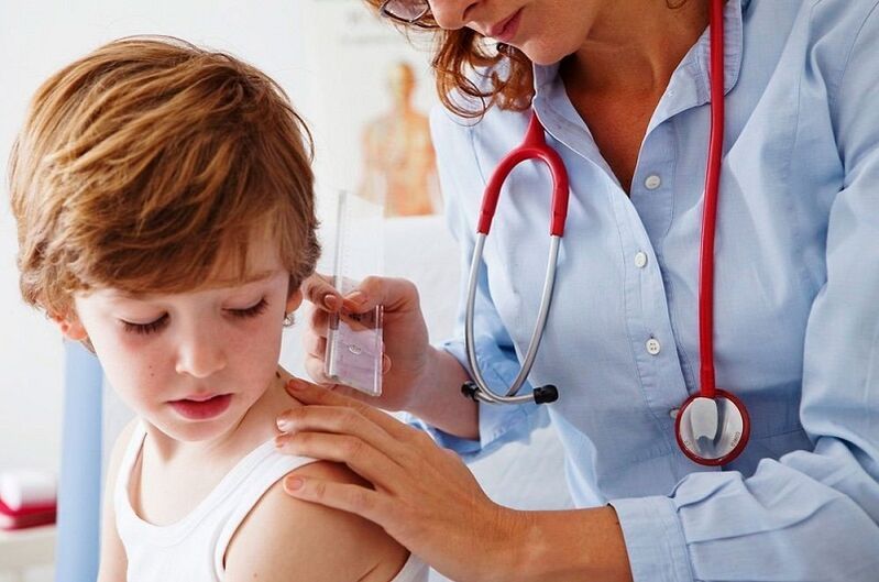 The doctor examines a child with papillomas on the body